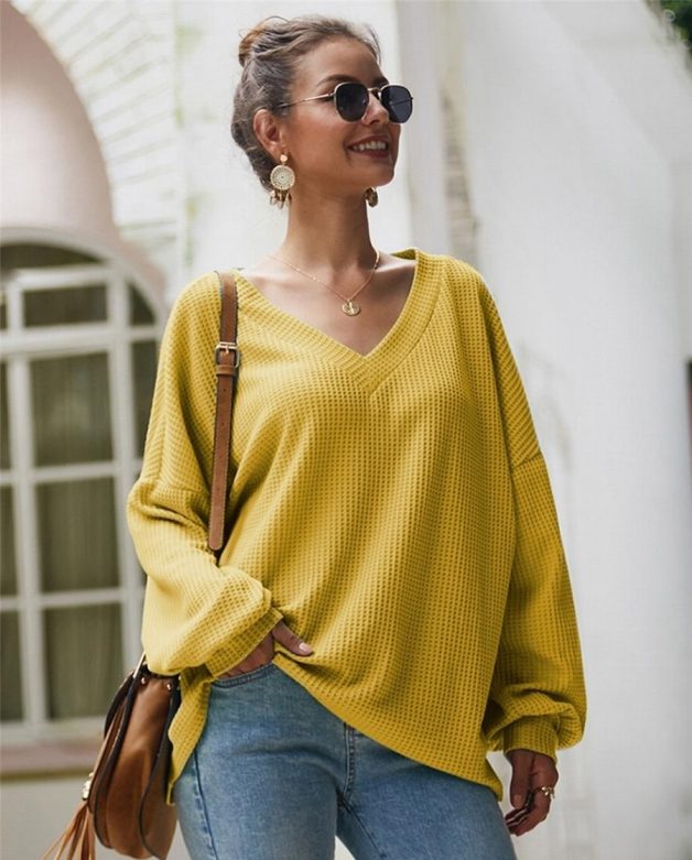 Imagem de mulher usando um suéter amarelo, uma das 10 peças de roupas indispensáveis para se ter no inverno